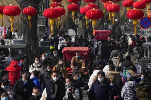 A trishaw driver wades through a crowded street at the frozen Houhai Lake in Beijing, Monday, Jan. 30, 2023. The outlook for the global economy is growing slightly brighter as China eases its zero-COVID policies and the world shows surprising resilience in the face of high inflation, elevated interest rates and Russia's ongoing war against Ukraine.(AP Photo/Andy Wong)