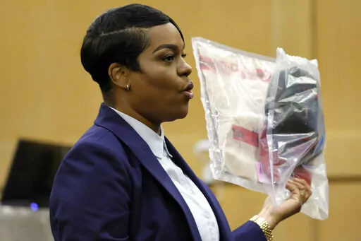 During her closing arguments in the XXXTentacion murder trial, Assistant State Attorney Pascale Achille holds up a camouflage hat with a red brim that was seen worn by shooting suspect Michael Boatwright in multiple surveillance videos included as evidence in the case, at the Broward County Courthouse in Fort Lauderdale, Fla., Tuesday, March 7, 2023. Emerging rapper XXXTentacion, born Jahseh Onfroy, 20, was killed during a robbery outside of Riva Motorsports in Pompano Beach in 2018, allegedly b