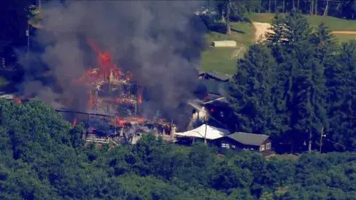 This image taken from video provided by WJLA shows crews battling a fire at Camp Airy for Boys in Thurmont, Md., on Wednesday, June 29, 2022. The building was empty when the fire broke out and no injuries have been reported, Frederick County Division of Fire & Rescue Services spokesperson Sarah Campbell said.  Residents and campers were not in the area of the fire, she said.   (WJLA via AP)