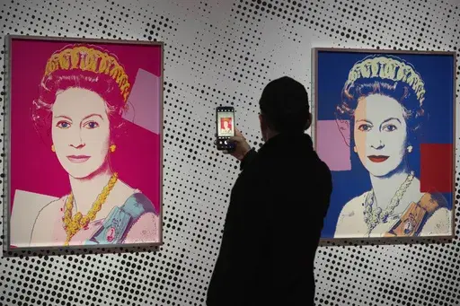 A man takes an image of a screen print depicting Queen Elizabeth II, one in a series of sixteen prints of four queens titled Reigning Queens, 1985, by Andy Warhol at museum Paleis Het Loo in Apeldoorn, Netherlands, Wednesday, Oct. 9, 2024, similar to a Warhol work stolen from a gallery in Oisterwijk, Netherlands, early Friday, Nov. 1, 2024. (AP Photo/Peter Dejong)