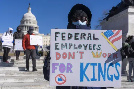 A federal employee, who asked not to use their name for fears over losing their job, protests with a sign saying "Federal Employees Don't Work for Kings" during the "No Kings Day" protest on Presidents Day in Washington, in support of federal workers and against recent actions by President Donald Trump and Elon Musk, Monday, Feb. 17, 2025, by the Capitol in Washington. (AP Photo/Jacquelyn Martin)