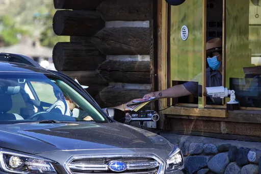 In this Monday, June 1, 2020 photo, a gate attendant at the North Entrance deals with visitors as the Montana entrances to Yellowstone National Park, in Wyoming, reopened after being closed due to COVID-19. On Friday, Dec. 23, 2022, The Associated Press reported on stories circulating online incorrectly claiming Yellowstone National Park officials have “closed down the park” due to a rising “volcanic uplift.” (Ryan Berry/Bozeman Daily Chronicle via AP, File)/Bozeman Daily Chronicle via A