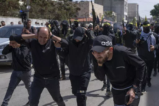 Palestinian gunmen shoot in the air during the funerals for Sanad Abu Atiyeh, 17 and Yazid al-Saadi, 23, in the West Bank refugee camp of Jenin, Jenin, Thursday, March 31, 2022. Israeli forces raided a refugee camp in the occupied West Bank early Thursday, setting off a gun battle in which two Palestinians were killed and 15 were wounded, the Palestinian Health Ministry said. (AP Photo/Nasser Nasser)