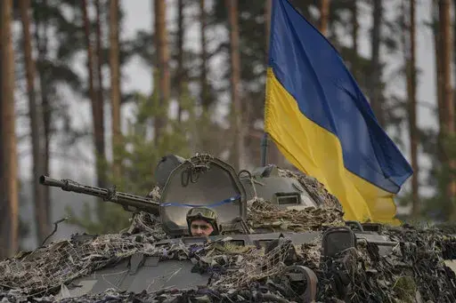 Ukrainian servicemen ride on an armored transporter driving through a Russian position overran by Ukrainian forces outside Kyiv, Ukraine, Thursday, March 31, 2022. Heavy fighting raged on the outskirts of Kyiv and other zones Thursday amid indications the Kremlin is using talk of de-escalation as cover while regrouping and resupplying its forces and redeploying them for a stepped-up offensive in eastern Ukraine.(AP Photo/Vadim Ghirda)