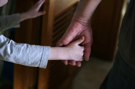 An autistic boy holds the hand of his adoptive father as they prepare to leave for a family outing from their home in Springfield, Mass., on Saturday, Dec. 12, 2015. Traditionally, autism was diagnosed only in kids with severe language and social impairments and unusual repetitious behaviors. But the definition gradually expanded, and autism is now shorthand for a group of milder, related conditions, too. (AP Photo/Charles Krupa, File)