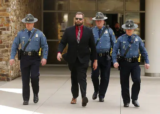 Arkansas State Troopers escort former Lonoke County sheriff's deputy Michael Davis, left center, after being convicted of negligent homicide on Friday, March 18, 2022, at the Cabot Readiness Center in Cabot, Ark.  Jurors acquitted Michael Davis of the more serious offense of manslaughter while finding him guilty of the misdemeanor charge in the death of 17-year-old Hunter Brittain during a June 23 traffic stop outside Cabot.  (Thomas Metthe/The Arkansas Democrat-Gazette via AP)