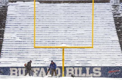 Grounds crew work to clear snow off the field at Highmark Stadium before an NFL football game between the Buffalo Bills and the Miami Dolphins in Orchard Park, N.Y., Saturday, Dec. 17, 2022. (AP Photo/Gene J. Puskar)