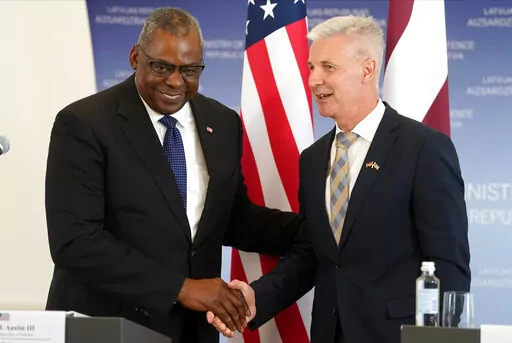 U.S. Secretary of Defense Lloyd Austin, left, and Latvian Minister of Defence Artis Pabriks shake hands during the press conference in Riga, Latvia, Wednesday, Aug. 10, 2022. (AP Photo/Roman Koksarov)