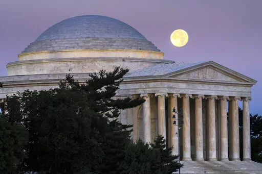 A full moon sets behind the Jefferson Memorial in Washington at dawn, Thursday, July 14, 2022. (AP Photo/J. David Ake)