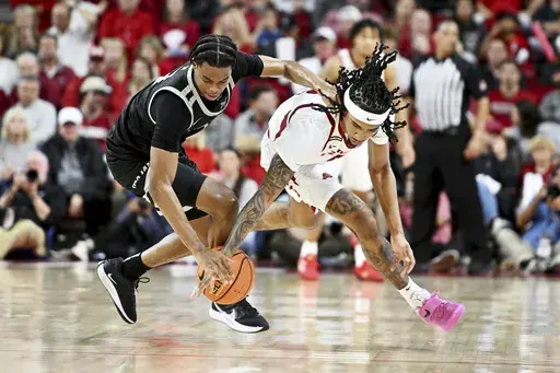 Little Rock guard Isaiah Lewis, left, and Arkansas guard Boogie Fland, right, go after a loose ball during the second half of an NCAA college basketball game Friday, Nov. 22, 2024, in Fayetteville, Ark. (AP Photo/Michael Woods)