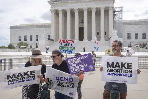Katie Mahoney, left, and Rev. Patrick Mahoney, chief strategy officer for Stanton Healthcare, an Idaho-based pregnancy center that does not provide abortions, read the text of a Supreme Court decision outside the Supreme Court on Thursday, June 27, 2024, in Washington. The Supreme Court cleared the way Thursday for Idaho hospitals to provide emergency abortions for now in a procedural ruling that left key questions unanswered and could mean the issue ends up before the conservative-majority cour