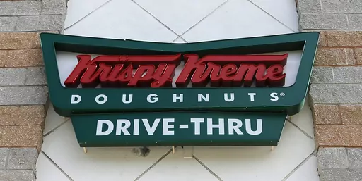 A Krispy Kreme Doughnuts sign is shown on Aug. 11, 2017, in Miami. More and more businesses are taking advantage of the total solar eclipse set to dim skies across North America on Monday, April 8, 2024. In the snacks department alone, Krispy Kreme is teaming up with Oreo to sell a limited doughnut-cookie creation. Sonic Drive-In is selling a “Blackout Slush Float.” (AP Photo/Alan Diaz, File)