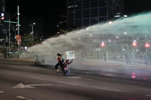 Police use water cannon to disperse demonstrators blocking a road during a protest against Israeli Prime Minister Benjamin Netanyahu's government, and calling for the release of hostages held in the Gaza Strip by the Hamas militant group, in Tel Aviv, Israel, Saturday, May 18, 2024. (AP Photo/Leo Correa)