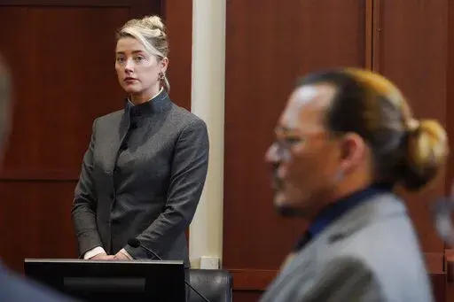 Actors Amber Heard and Johnny Depp watch as the jury leaves the courtroom for a lunch break at the Fairfax County Circuit Courthouse in Fairfax, Va., Monday, May 16, 2022. A new court filing on Friday, July 8, 2022, from Heard's legal team, alleges one of the jurors in the defamation case filed against her by her ex-husband Depp served improperly. (AP Photo/Steve Helber, Pool, File)