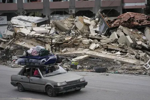 Displaced residents drive past the rubble of destroyed buildings as they return to their villages, following a ceasefire between Israel and Hezbollah that went into effect on Wednesday, Nov. 27, 2024, in Tyre, southern Lebanon. (AP Photo/Hussein Malla)