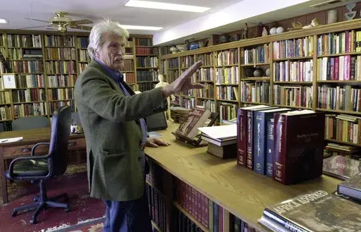 Schuyler Jones talks about the bookcases he built that line his library Monday, Feb. 6, 2006, in Wichita, Kansas. Jones, a globe-trotting American adventurer whose exploits drew comparisons to iconic movie character Indiana Jones, has died. He was 94. Jones' step-daughter, Cassandra Da'Luz Vieira-Manion, posted on her Facebook page that Jones died on May 17, 2024. (Dave Williams/The Wichita Eagle via AP)
