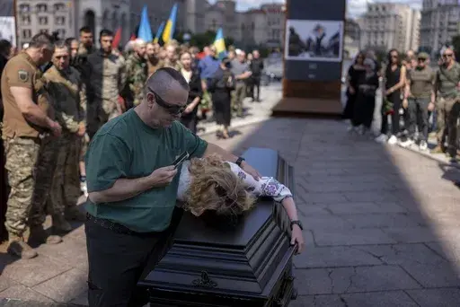 Partner of British combat medic, volunteer, Peter Fouche, 49 who was killed on June 27 during his work in East Ukraine, mourns during the funeral ceremony on the city's main square in Kyiv, Ukraine, Saturday, July 6, 2024. Peter was founder of a charity organization, which provides vehicles, drones and other needs to Ukrainian servicemen. (AP Photo/Alex Babenko)