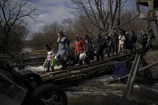 Ukrainians cross an improvised path under a destroyed bridge while fleeing Irpin, on the outskirts of Kyiv, Ukraine, Wednesday, March 9, 2022. (AP Photo/Felipe Dana)
