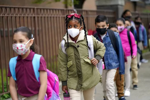 Students line up to enter Christa McAuliffe School in Jersey City, N.J., April 29, 2021. New Jersey Gov. Phil Murphy will end a statewide mask mandate to protect against COVID-19 in schools and child care centers, his office said Monday, Feb 7, 2022. (AP Photo/Seth Wenig, File)
