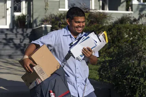 United States Postal Service letter carrier Gabriel Peña carries mail in Los Angeles on March 22, 2024. On Friday, June 7, 2024, the U.S. government issues its May jobs report. (AP Photo/Damian Dovarganes, File)