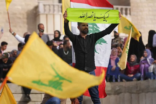 A Hezbollah supporter holds up an Arabic banner that reads: "At your service Nasrallah," as he attends an election campaign, in Baalbek, east Lebanon, Friday, May 13, 2022. Despite a devastating economic collapse and multiple other crises gripping Lebanon, the culmination of decades of corruption and mismanagement, the deeply divisive issue of Hezbollah's weapons has been at the center of Sunday's vote for a new 128-member parliament. (AP Photo/Hussein Malla)