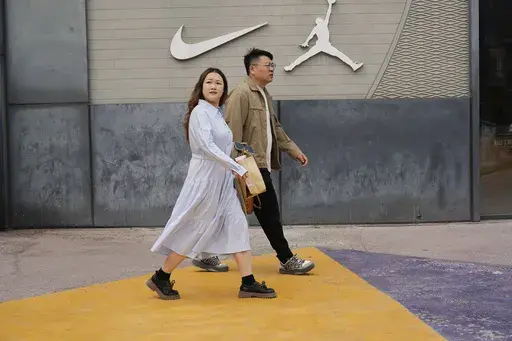 Shoppers walk near a Nike store in Beijing, China, Tuesday, April 8, 2025. (AP Photo/Ng Han Guan)