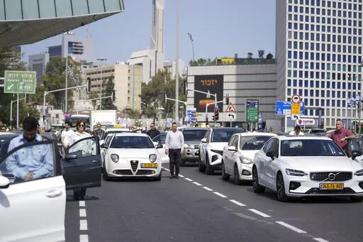 Israelis stand still next to their cars on a main road as a two-minute siren sounds in memory of victims of the Holocaust in Tel Aviv, Israel, Thursday, April 28, 2022. Holocaust remembrance day is one of the most solemn on Israel's calendar with restaurants and places of entertainment shut down, and radio and TV programming focused on Holocaust documentaries and interviews with survivors. (AP Photo/Ariel Schalit)