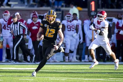 Missouri quarterback Brady Cook, left, runs past Arkansas linebacker Chris Paul Jr., right, during the second quarter of an NCAA college football game Friday, Nov. 25, 2022, in Columbia, Mo. (AP Photo/L.G. Patterson)