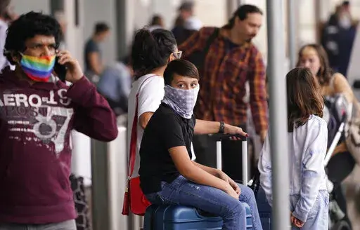 To prevent the spread of COVID-19, air travelers wear masks at Love Field in Dallas, Friday, Dec. 31, 2021. Flight cancellations surged again on the last day of 2021, with airlines blaming it on crew shortages related to the spike in COVID-19 infections.  The new year is bringing more of the same old misery that air travelers in the United States have been enduring for more than a week. Airlines are blaming wintry weather and high numbers of sickouts due to the rising number of COVID-19 infectio
