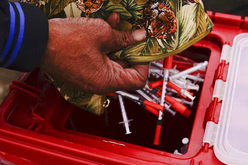 Keith Lewis disposes of used syringes at a needle exchange run by Camden Area Health Education Center in Camden, N.J., Thursday, Feb. 24, 2022.  Four companies involved in the opioid industry are finalizing settlements over the addiction crisis in the U.S. in deals that could total $26 billion over 18 years. (AP Photo/Matt Rourke)