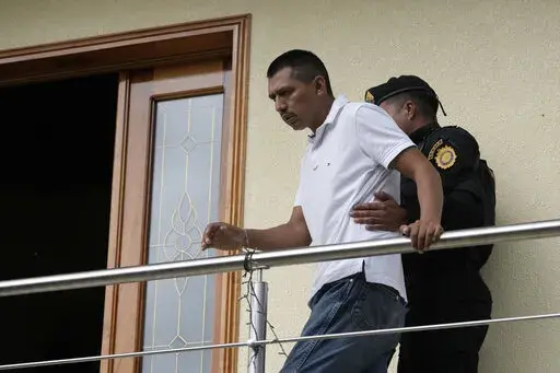 A detainee who identified himself as Felipe Diego Alonzo is escorted on his property during a police raid against alleged migrant smugglers near the Mexican border in Huehuetenango, Guatemala, Tuesday, Aug. 2, 2022. Police identified Alonzo as the leader. (AP Photo/Moises Castillo)