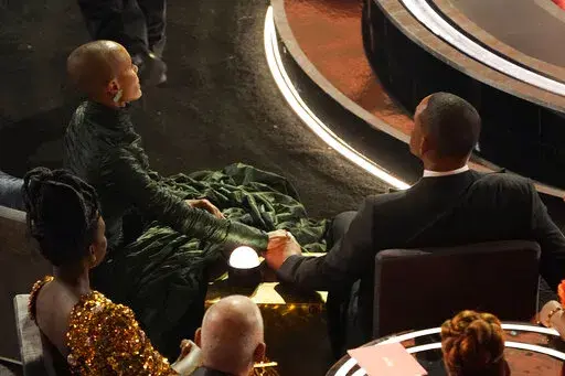 Jada Pinkett Smith, left, and Will Smith hold hands in the audience at the Oscars on March 27, 2022, at the Dolby Theatre in Los Angeles. The stunning physical altercation between actor Will Smith and comedian Chris Rock at the 94th Academy Awards on Sunday has sparked debate about the appropriate ways for Black men to publicly defend Black women against humiliation and abuse. (AP Photo/Chris Pizzello, File)