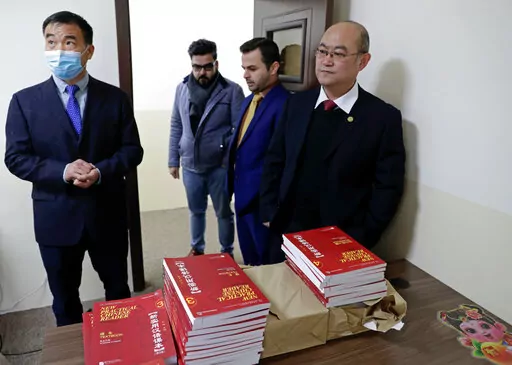 Chinese lecturer, Zhiwei Hu, left, teachers and officials of the Chinese Language Department stand in front of Chinese language books intended for students in Salahaddin University in Irbil, Iraq, Wednesday, Jan. 19, 2021. The Chinese language school in northern Iraq is attracting students who hope to land jobs with a growing number of Chinese companies in the oil, infrastructure, construction, and telecommunications sectors in the region. (AP Photo/Khalid Mohammed)