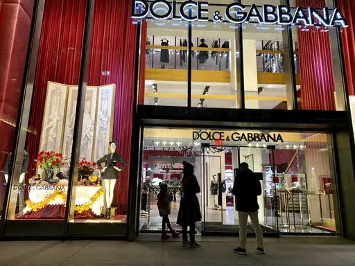 People stand outside the Dolce & Gabbana store on Fifth Avenue, Nov. 21, 2021, in New York. Dolce & Gabbana announced Monday, Jan. 31, 2022 that it will drop the use of animal fur in all its collections starting this year, and transition to eco-friendly faux fur. The Milan fashion house joins other luxury brands, including Armani, Gucci, Prada and Moncler, in adhering to guidelines set by the Fur Free Alliance, a network of animal rights groups around the world. (AP Photo/Pamela Hassell, file)