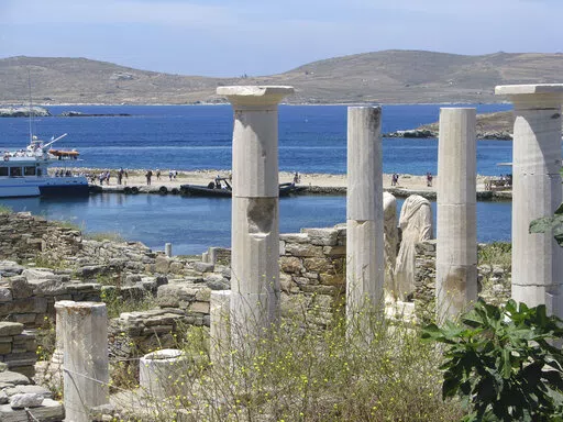 Ancient statues and columns from a millennia-old house stand just above the landing dock in the archaeological park at Delos, Greece, on May 25, 2019. The tiny island, a short boat ride from party-central Mykonos, was considered holy by ancient Greeks.  (AP Photo/Giovanna Dell’Orto)