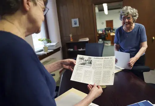Benedictine sisters, Rose Marie Stallbaumer, left, and Barbara McCracken, right, look through corporate resolution archives and newspaper clippings at the Mount St. Scholastica monastery in Atchison, Kan., Tuesday, July 16, 2024. For the past two decades the community has participated in activist investing, a process in which they partner with other religious organizations to buy the stocks of companies they hope to positively influence. (AP Photo/Jessie Wardarski)