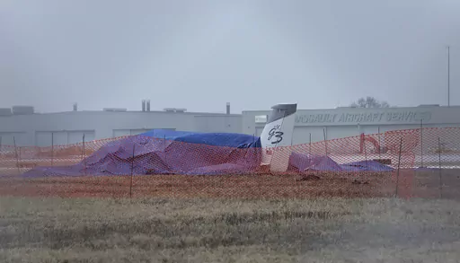 The wreckage of a single-engine Cirrus SR 22 aircraft is covered by a blue tarp near a runway at the Bill and Hillary Clinton National Airport on Monday, Jan. 22, 2024, after it crashed on Sunday in Little Rock, Ark. The pilot of the aircraft was pronounced dead at the scene and was the only individual on board at the time of the incident. (Colin Murphey /Arkansas Democrat-Gazette via AP)