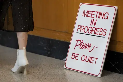 A person walks by a sign for a meeting in progress at the Oregon state Capitol on Wednesday, Dec. 11, 2024, in Salem, Ore. (AP Photo/Jenny Kane)