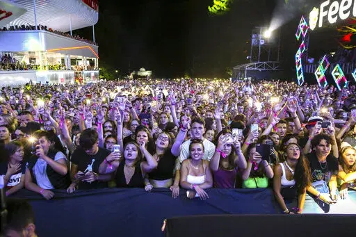 Audience enjoy Miley Cyrus performing at Sunny Hill Festival in Pristina, Kosovo Friday, Aug. 2, 2019. Kosovo’s central government and authorities in the capital joined forces on Monday, June 20, 2022 to bring back home an international music festival founded by the father of singer-songwriter Dua Lipa which had been moved following a dispute with its organizers. (AP Photo/Visar Kryeziu, file)