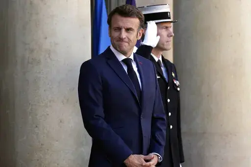 French President Emmanuel Macron greets journalists as he arrives to welcome German Chancellor Olaf Scholz, unseen, at the Elysee Palace in Paris, Wednesday, Oct. 26, 2022. French President Emmanuel Macron is scheduled to meet in Paris with German Chancellor Olaf Scholz amid divergences between the two neighbors and key European Union allies over EU strategy, defense and economic policies. (AP Photo/Christophe Ena)