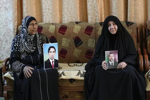 Nidal Ali, right, and Nawal Sweidan hold photos of their missing sons in Mahmoudiya, south of Baghdad, Iraq, Tuesday, March 28, 2023. Their sons were both kidnapped by extremist groups in 2014. Though active conflict in Iraq has largely subsided, many are still waiting to learn the fate of missing loved ones who disappeared during the US invasion, the subsequent civil war, or during the war against the Islamic State. (AP Photo/Hadi Mizban)