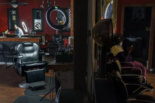 The barber chair where Sherman Peebles used to cut hair on Saturdays sits empty at Overflo Beauty and Barber Shop in Columbus, Ga., Wednesday, March 9, 2022. In late September, as Peebles, who also worked as a sheriff's deputy, lay in a hospital bed, COVID-19's toll reached 675,000, surpassing the number of Americans killed by the Spanish flu pandemic a century ago. He died at age 49 the next day. Months later, his best friend and shop owner, Gerald Riley, still arrives at the shop each Saturday