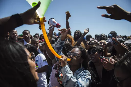 A crowd of party-goers cheer for a woman drinking from a beer bong during Orange Crush on Tybee Island, Ga., April 16, 2016. Thousands of Black college students expected this weekend for an annual spring bash at Georgia's largest public beach shouldn't expect a warm welcome. Tybee Island's city leaders are bringing in dozens of extra police officers and using barricades to block parking lots and residential streets during Orange Crush, a sprawling beach party begun three decades ago. (Josh Galem