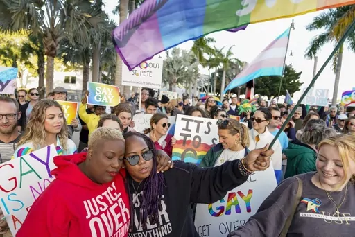 Florida House Representative Michele Rayner, left, hugs her spouse, Bianca Goolsby, during a march at city hall in St. Petersburg, Fla., on Saturday, March 12, 2022, to protest the controversial "Don't say gay" bill passed by Florida's Republican-led legislature and now on its way to Gov. Ron DeSantis' desk. Florida's state government and LGBTQ+ advocates have settled a lawsuit challenging a law that bars teaching about sexual orientation and gender identity in public schools. (Martha Asencio-Rh