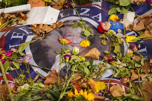 A flag carrying a portrait of Queen Elizabeth II is covered in flowers the day after her funeral, in London's Green Park, Tuesday, Sept. 20, 2022. The Queen, who died aged 96 on Sept. 8, was buried at Windsor alongside her late husband, Prince Philip, who died last year. (AP Photo/Vadim Ghirda)