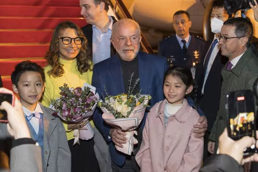 In this photo released by Xinhua News Agency, Brazilian President Luiz Inacio Lula da Silva, center, and first lady Rosangela Silva, second left, receive flowers presented by children from the Shanghai Children's Palace of the China Welfare Institute upon arrival in Shanghai, China on Wednesday, April 12, 2023. Lula was in the Chinese financial hub of Shanghai on Thursday in a bid to boost ties with the South American giant's biggest trade partner and win political support for attempts to mediat