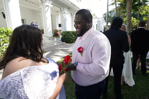 Sarah Horton, left, and Shackeem Frankson exchange rings as they get married during a Valentine's Day group wedding ceremony, Monday, Feb. 14, 2022, outside the Flagler Museum in Palm Beach, Fla. The pair were one of nine couples married by the Clerk of the Circuit Court & Comptroller for Palm Beach County during the annual event. (AP Photo/Wilfredo Lee)