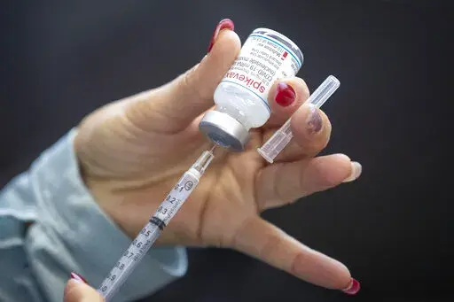 A person draws out Moderna vaccine during a drive through COVID-19 vaccine clinic at St. Lawrence College in Kingston, Ontario, on Sunday Jan.  2, 2022.  (Lars Hagberg /The Canadian Press via AP)
