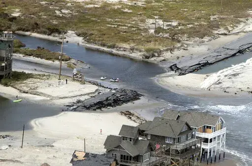 This aerial photo taken during a helicopter tour, on Tuesday, Aug. 30, 2011, with a group of federal and state officials, shows a section of Highway 12 at the edge of Rodanthe, N.C., that was destroyed by Hurricane Irene. A bridge that will allow locals and tourists to avoid the perennially washed-out route on North Carolina’s Outer Banks is set to open to traffic in April 2022. (Chris Seward/The News & Observer via AP, File)
