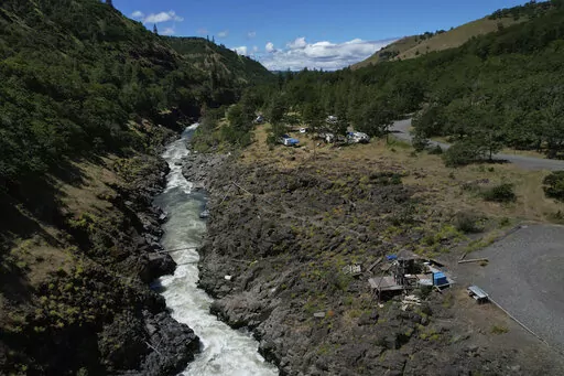 Water rushes through Lyle Falls in the Klickitat River, a tributary that runs into the Columbia River, on Sunday, June 19, 2022, in Lyle, Wash. For generations, Indigenous people have fished for salmon and trout from scaffolds perched just above the sacred water. (AP Photo/Jessie Wardarski)